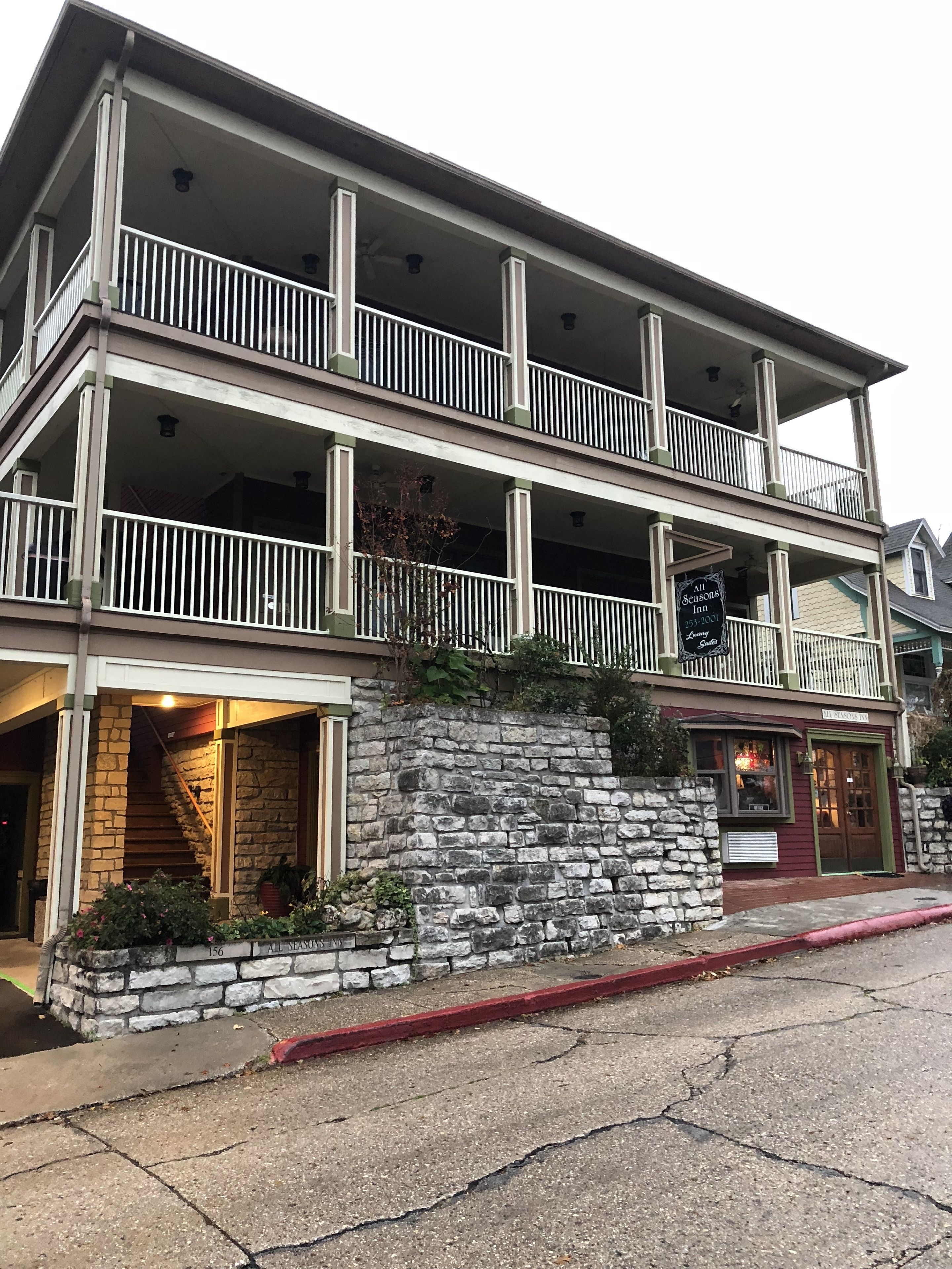 Un bâtiment à deux étages avec une façade en pierre, un balcon à l’étage supérieur et une enseigne indiquant qu’il s’agit d’une auberge saisonnière.