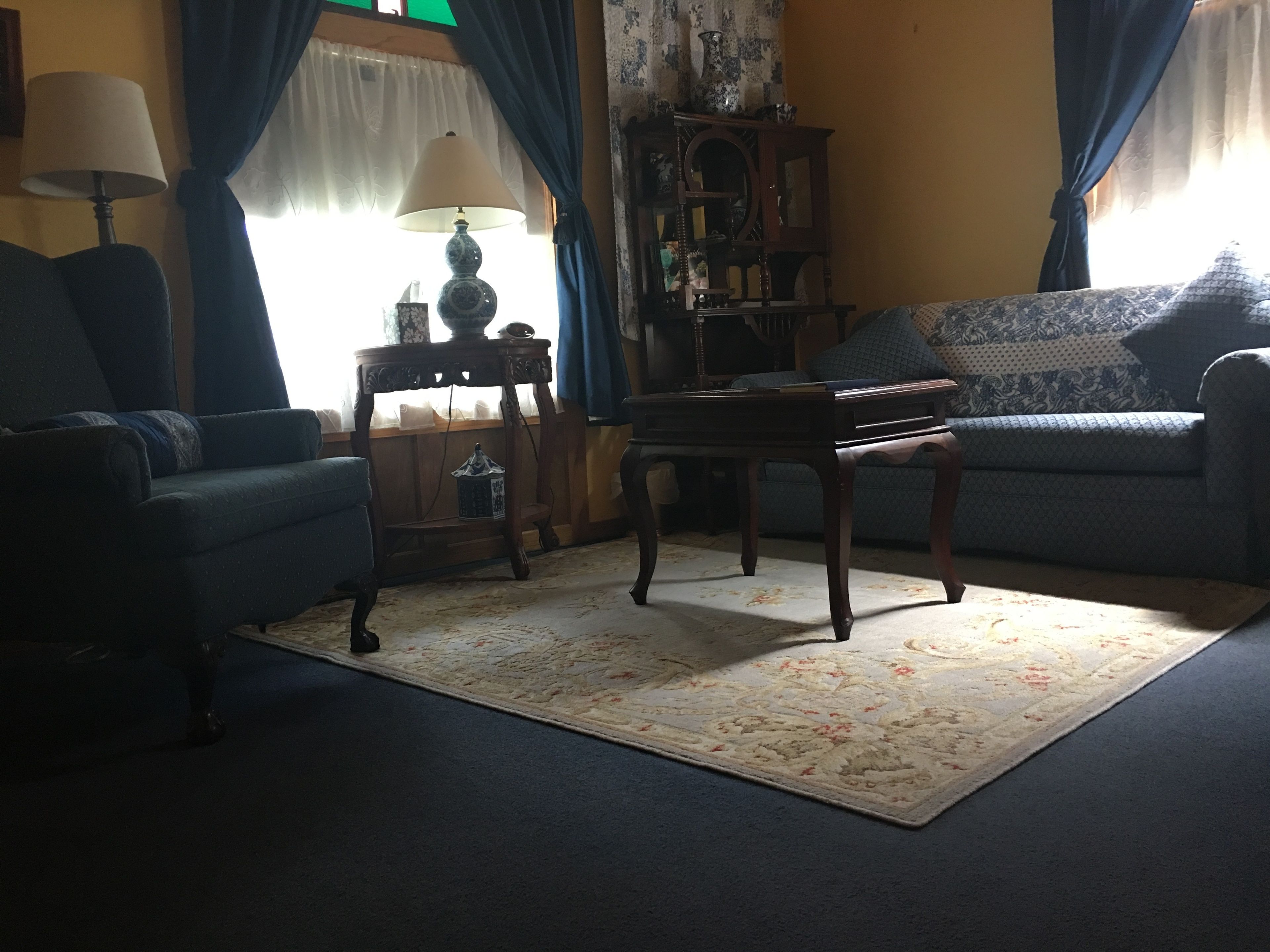 A living room with a sofa, a table, a lamp, and a cabinet.