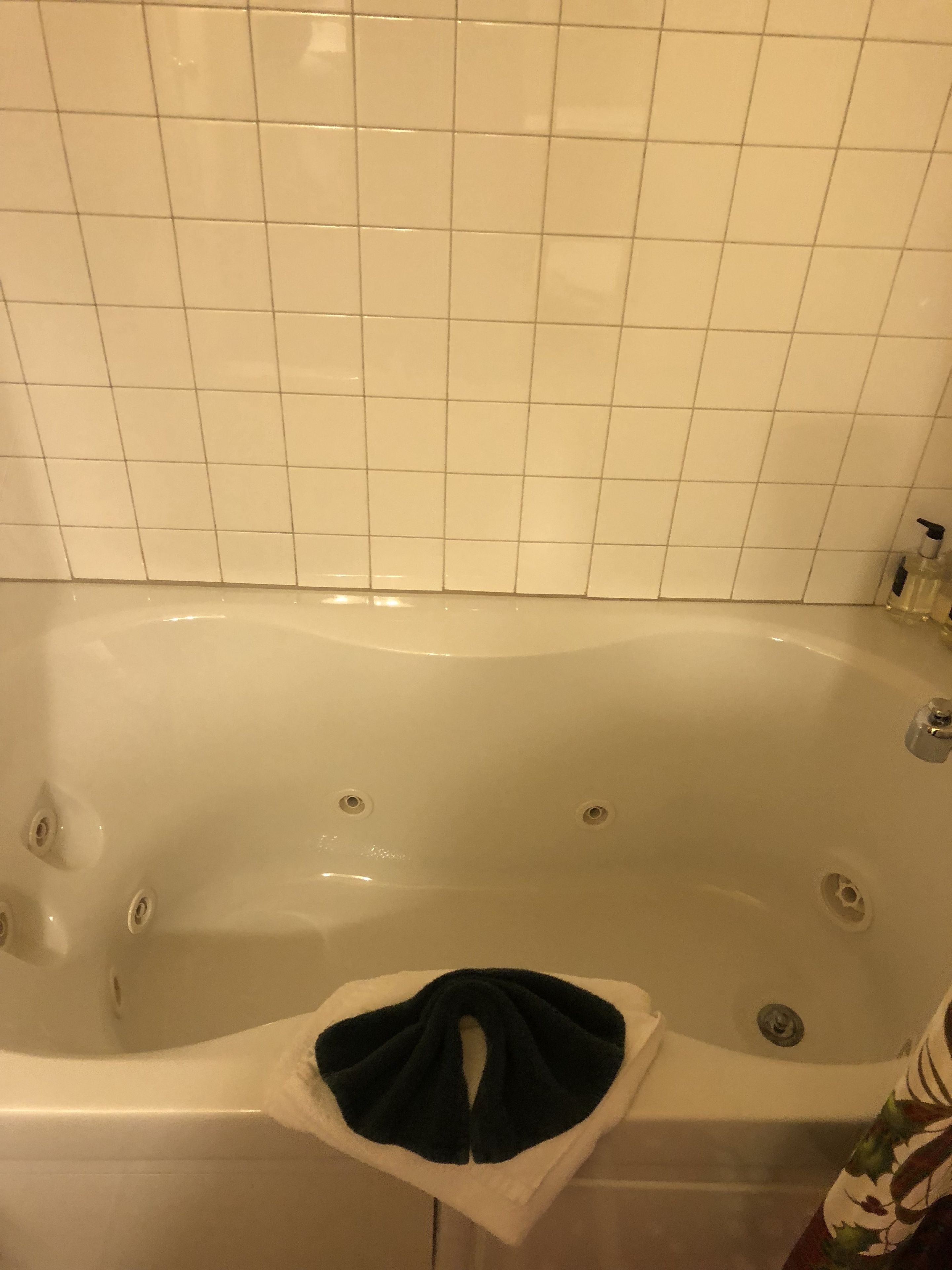 A bathtub with a white towel and a bottle of shampoo.