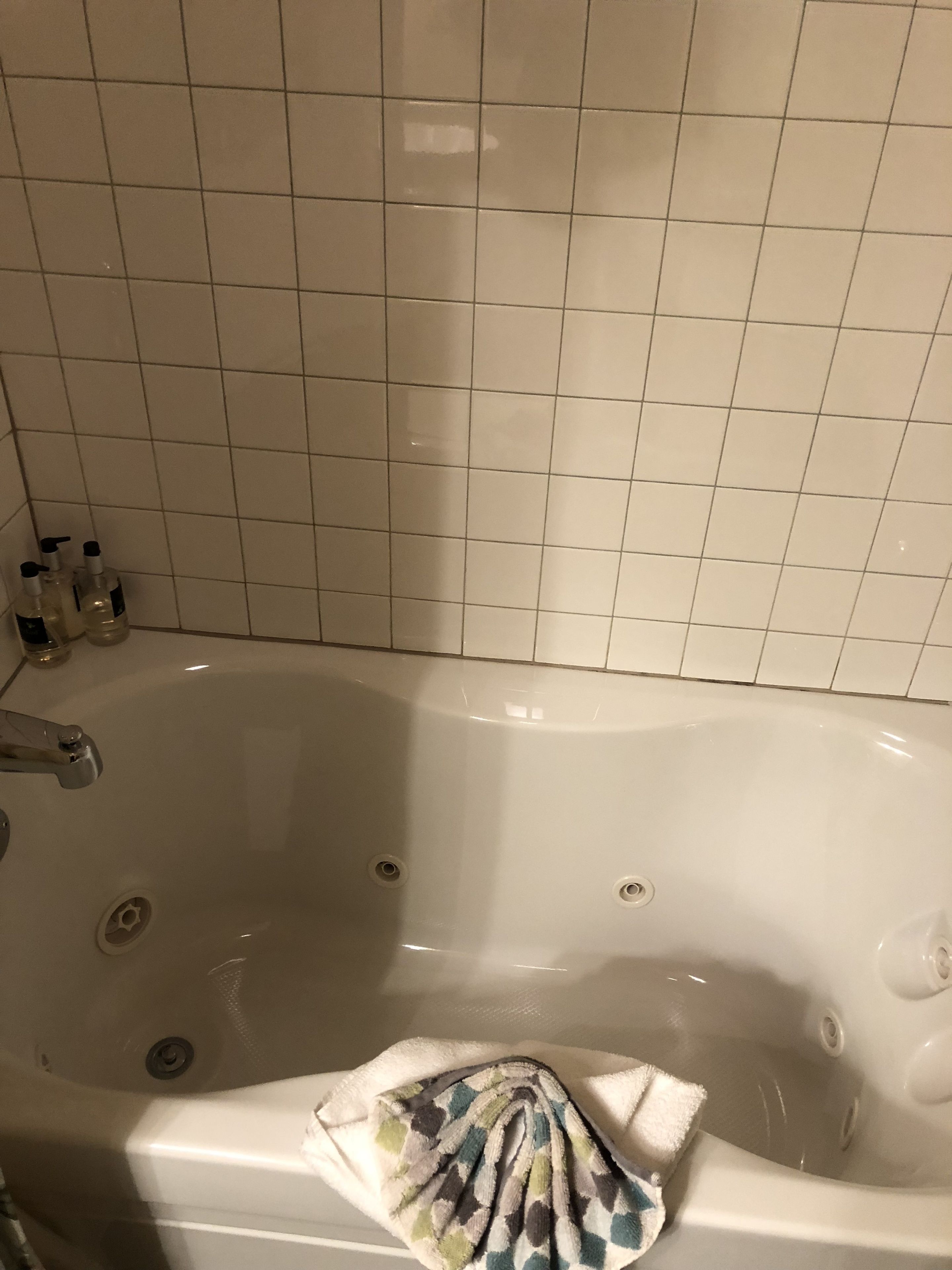 Ein Badezimmer mit einer weißen Badewanne, einem Handtuch und Toilettenartikeln am Rand.