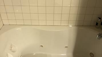 Un baño con una bañera blanca, una toalla azul y un revestimiento de azulejos blancos.