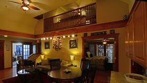 A spacious dining area with a high ceiling, a ceiling fan, and a staircase leading to an upper level. - All Seasons Inn (Eureka Springs)