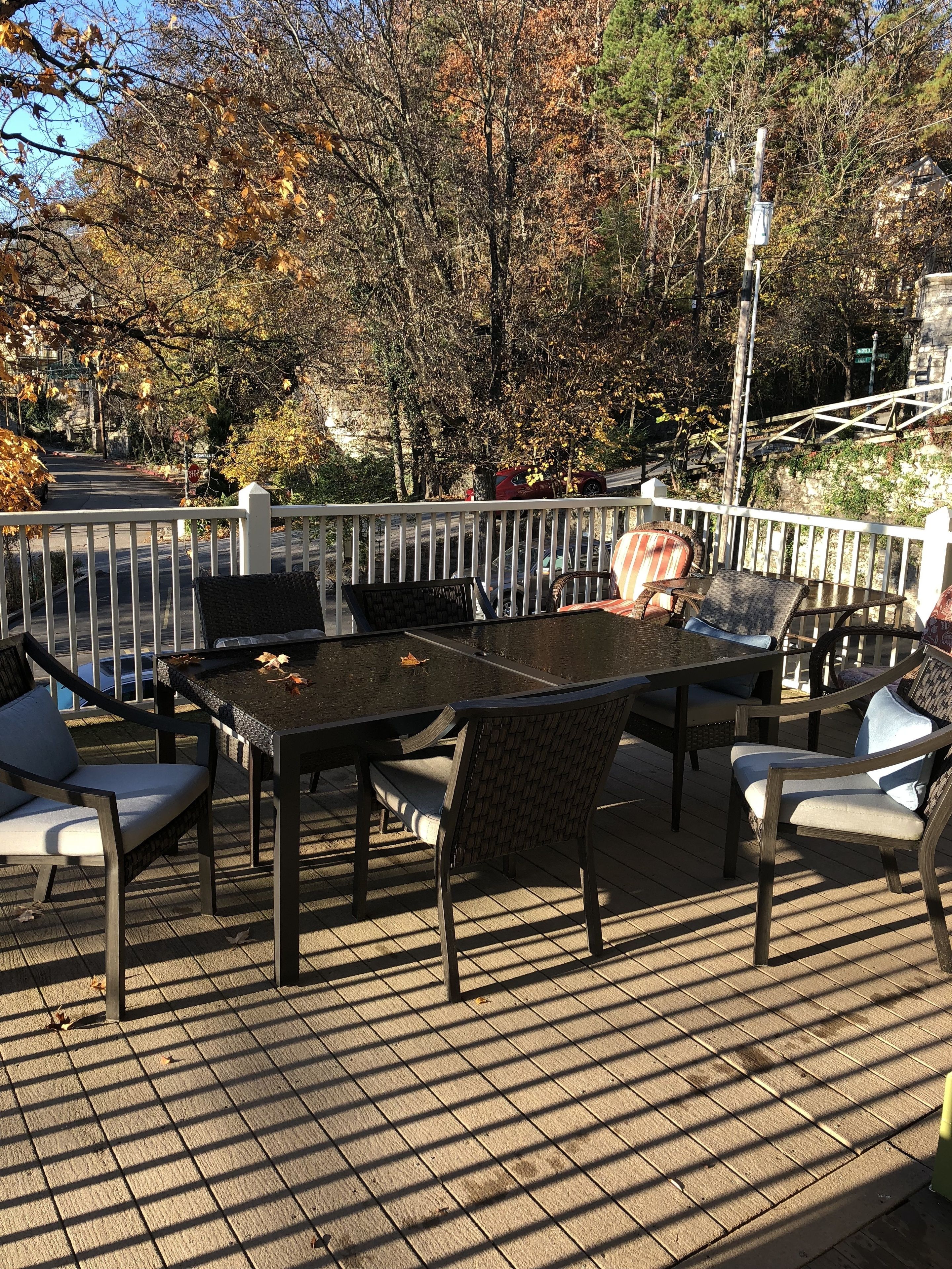 An outdoor deck with a table and chairs, surrounded by a white railing.