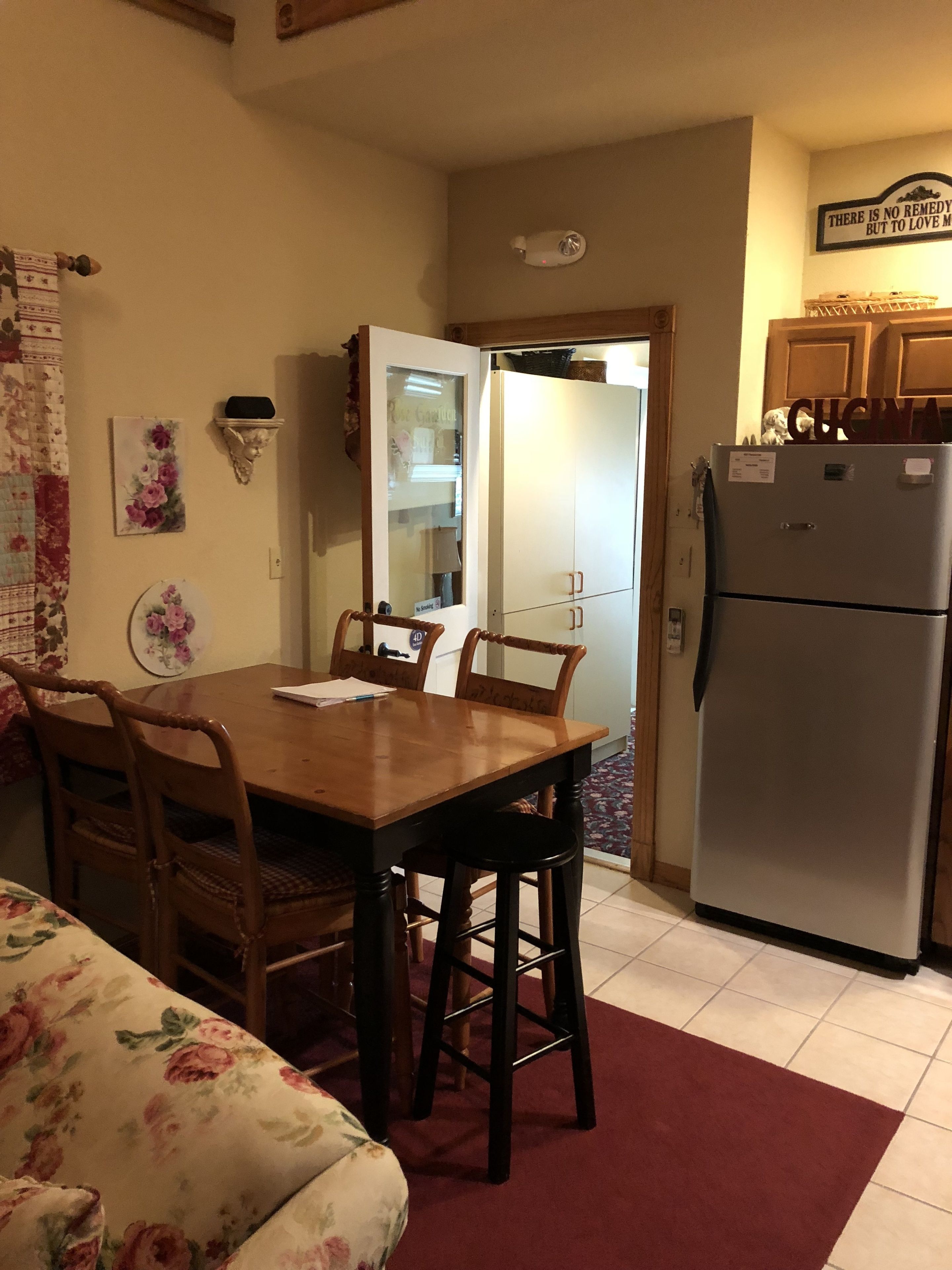 A compact kitchen with a dining table, chairs, a refrigerator, and a microwave.