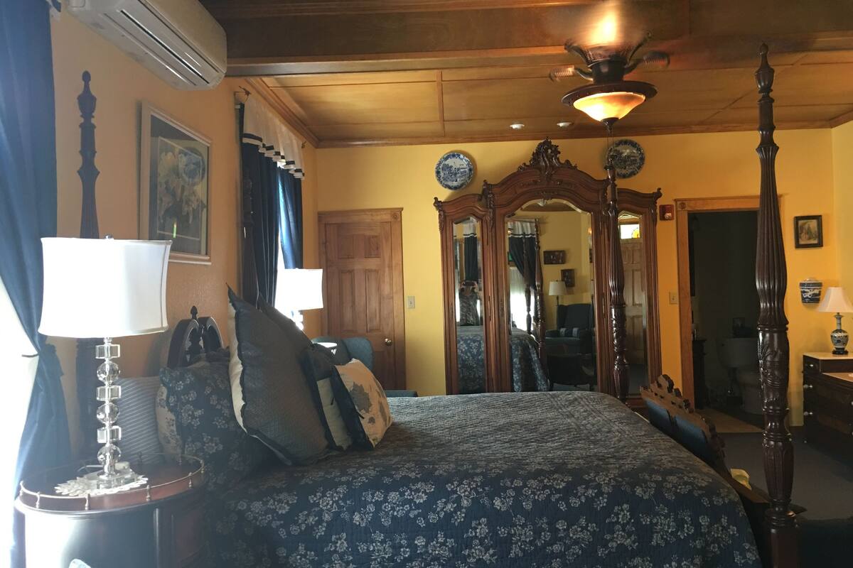 Quarto com uma cama grande, teto de madeira, espelho e ventilador de teto.