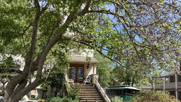 A building with a staircase leading to a porch with two chairs. - All Seasons Inn (Eureka Springs)