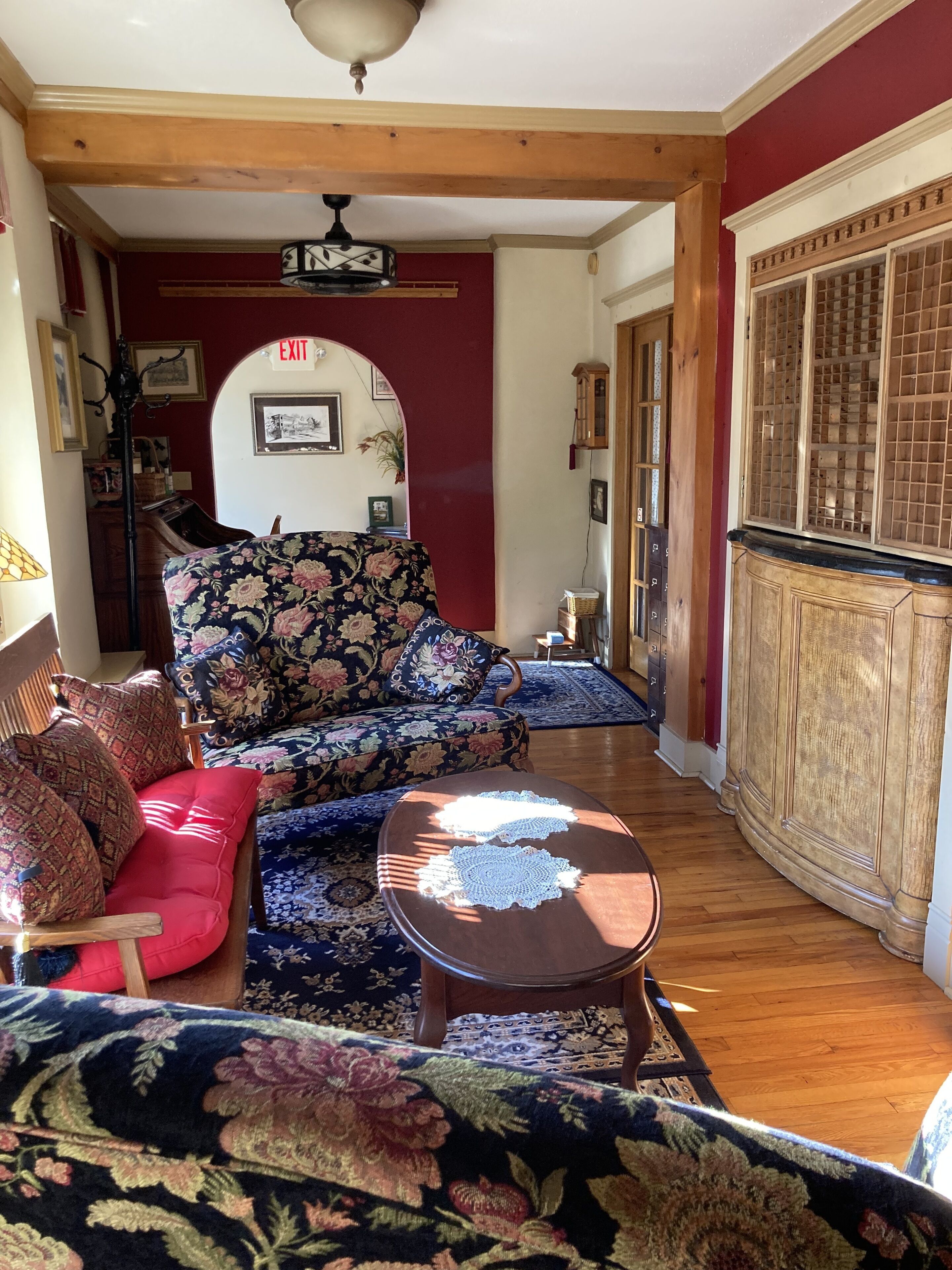 A cozy living room with a floral sofa, a red armchair, and a wooden coffee table.
