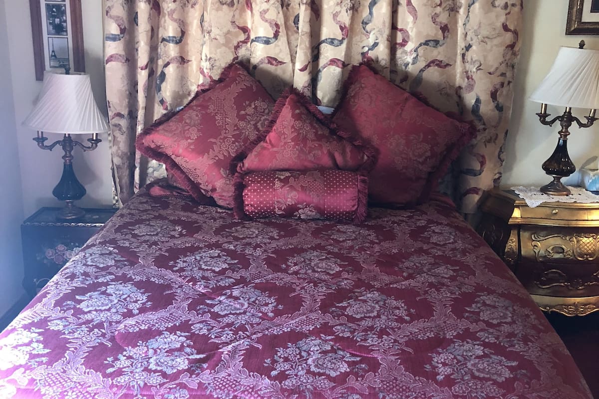 Quarto com cama grande, cortinas elaboradas e abajur clássico.