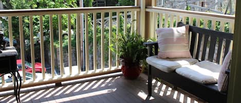 A wooden deck with a bench and potted plants.