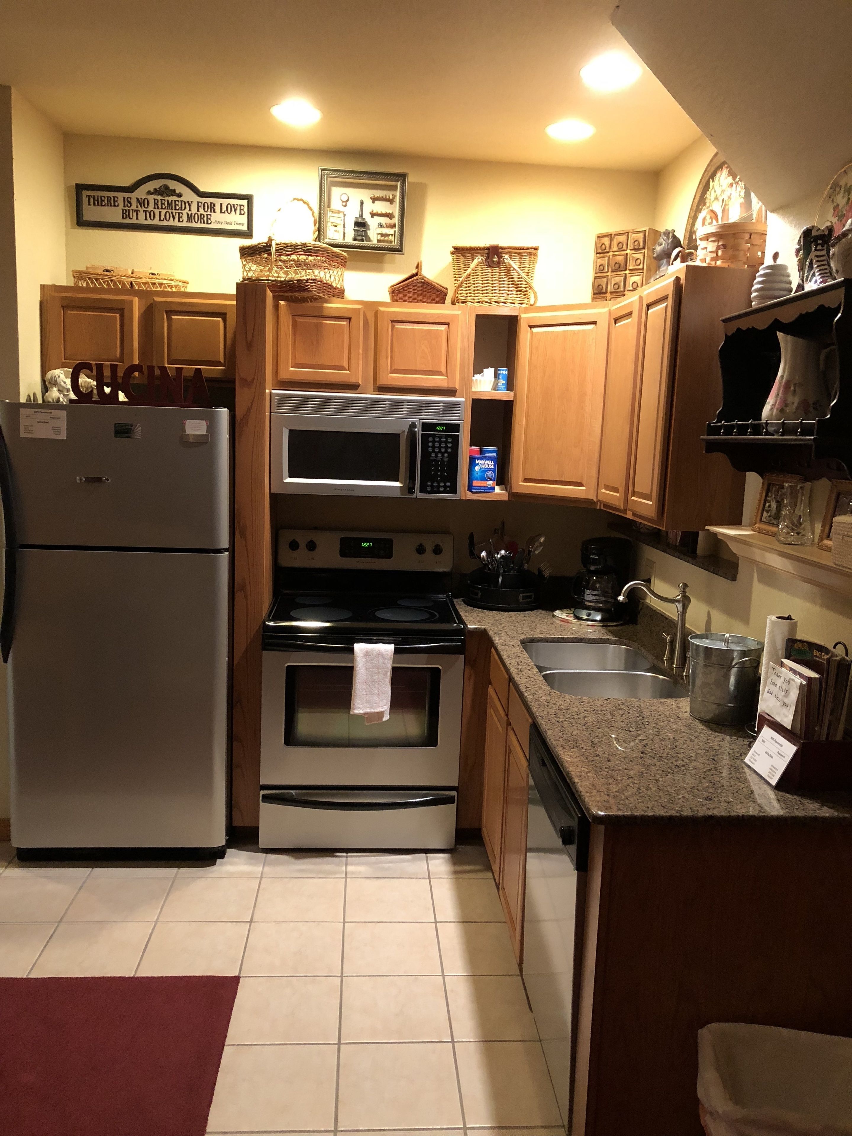 A kitchen with wooden cabinets, a stainless steel refrigerator, a microwave, an oven, and a granite countertop.