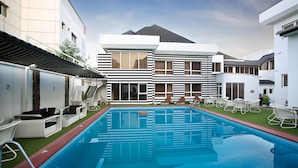Ein modernes Hotel mit Swimmingpool, Sitzgelegenheiten im Freien und einem gepflegten Rasen.