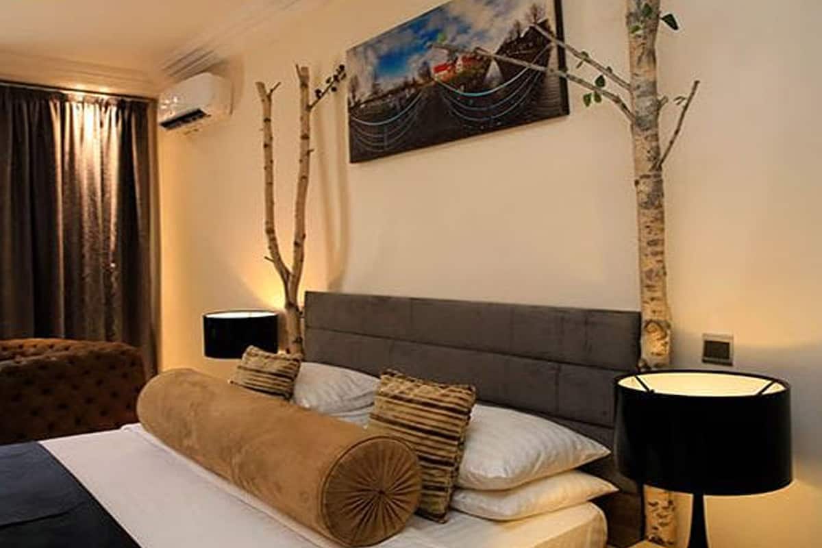 Ein Hotelzimmer mit Bett, Stuhl, Gemälde und Lampe.