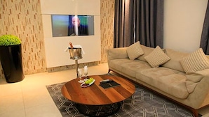 Ein modernes Wohnzimmer mit einem beigen Sofa, einem Holztisch und einem großen Fenster.