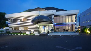 Een modern hotel met een ruime entreekap, brede trappen en een parkeerplaats.