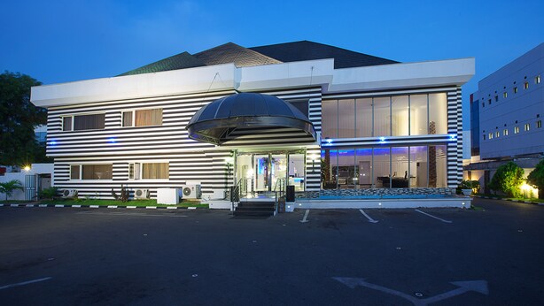 Ein modernes Hotel mit einer großzügigen Eingangsvorbau, breiten Stufen und einem Parkplatz.