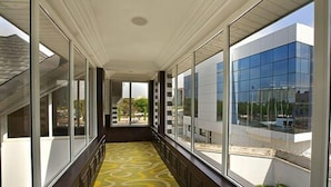 Ein Korridor mit großen Fenstern, einem gemusterten Teppich und Blick auf ein modernes Gebäude.