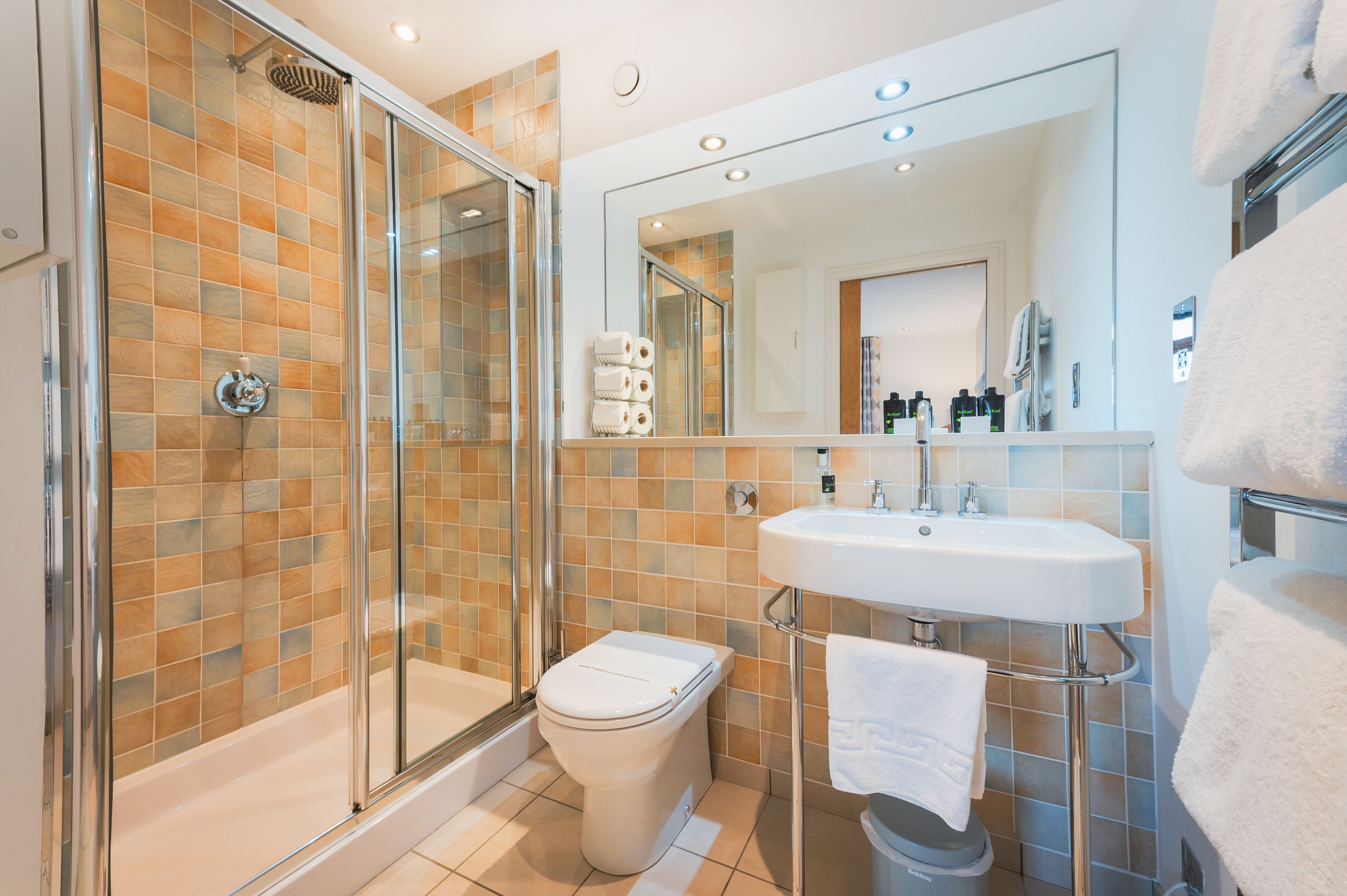 A modern bathroom with a glass-enclosed shower, a white sink, and a toilet.