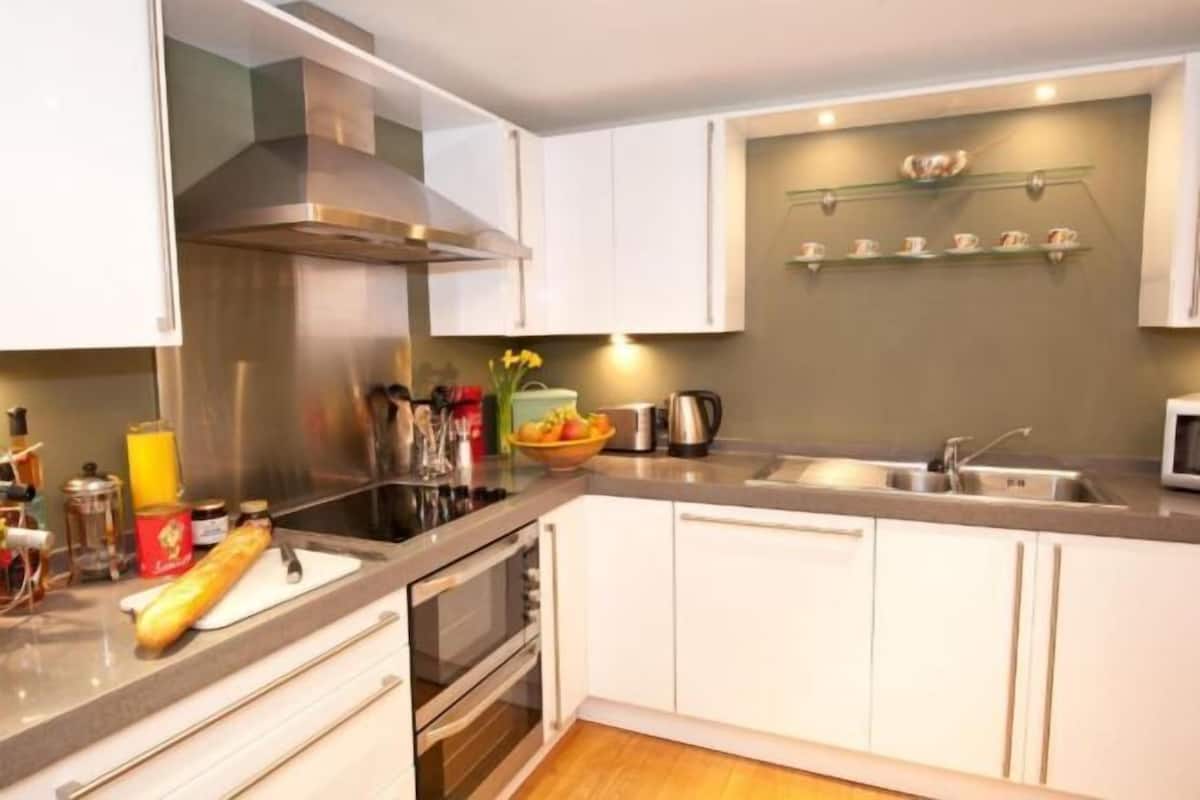 Une cuisine moderne avec des armoires blanches, des appareils en acier inoxydable et un four à micro-ondes.