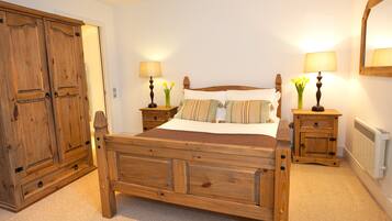 A wooden four-poster bed with a nightstand on each side, a wooden wardrobe, and a radiator on the wall.