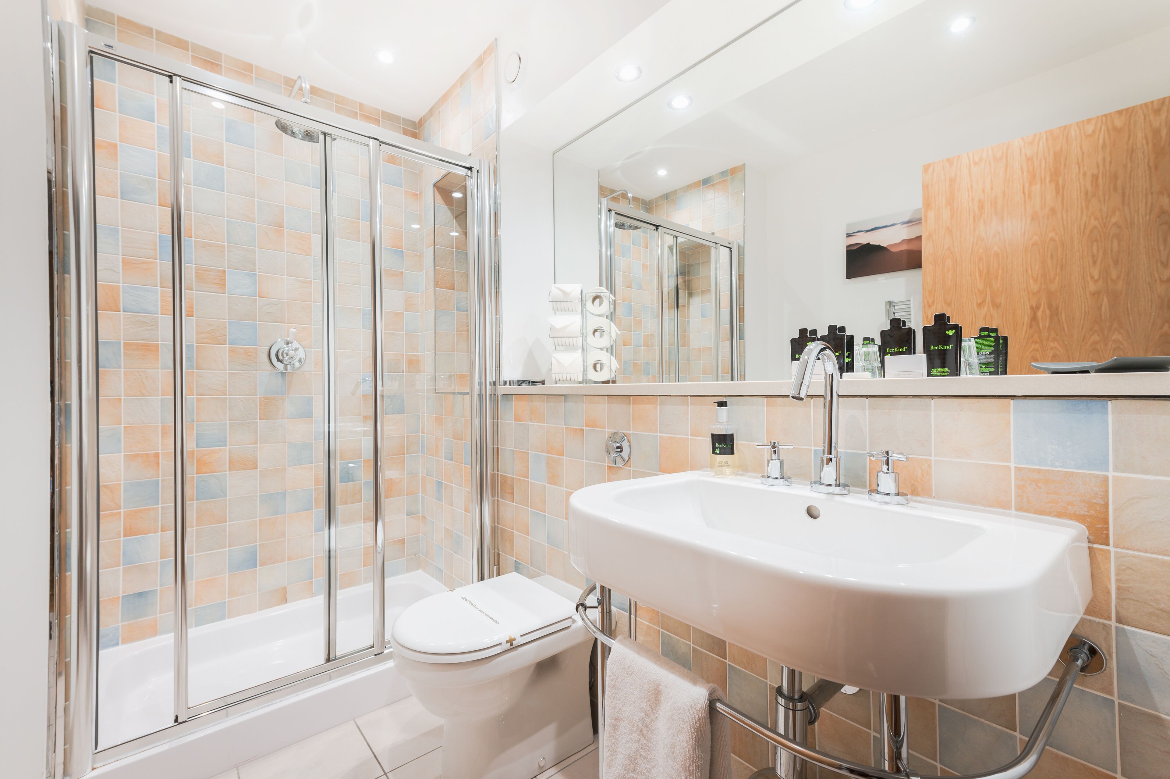 A modern bathroom with a glass-enclosed shower, a white sink, and a wooden vanity.