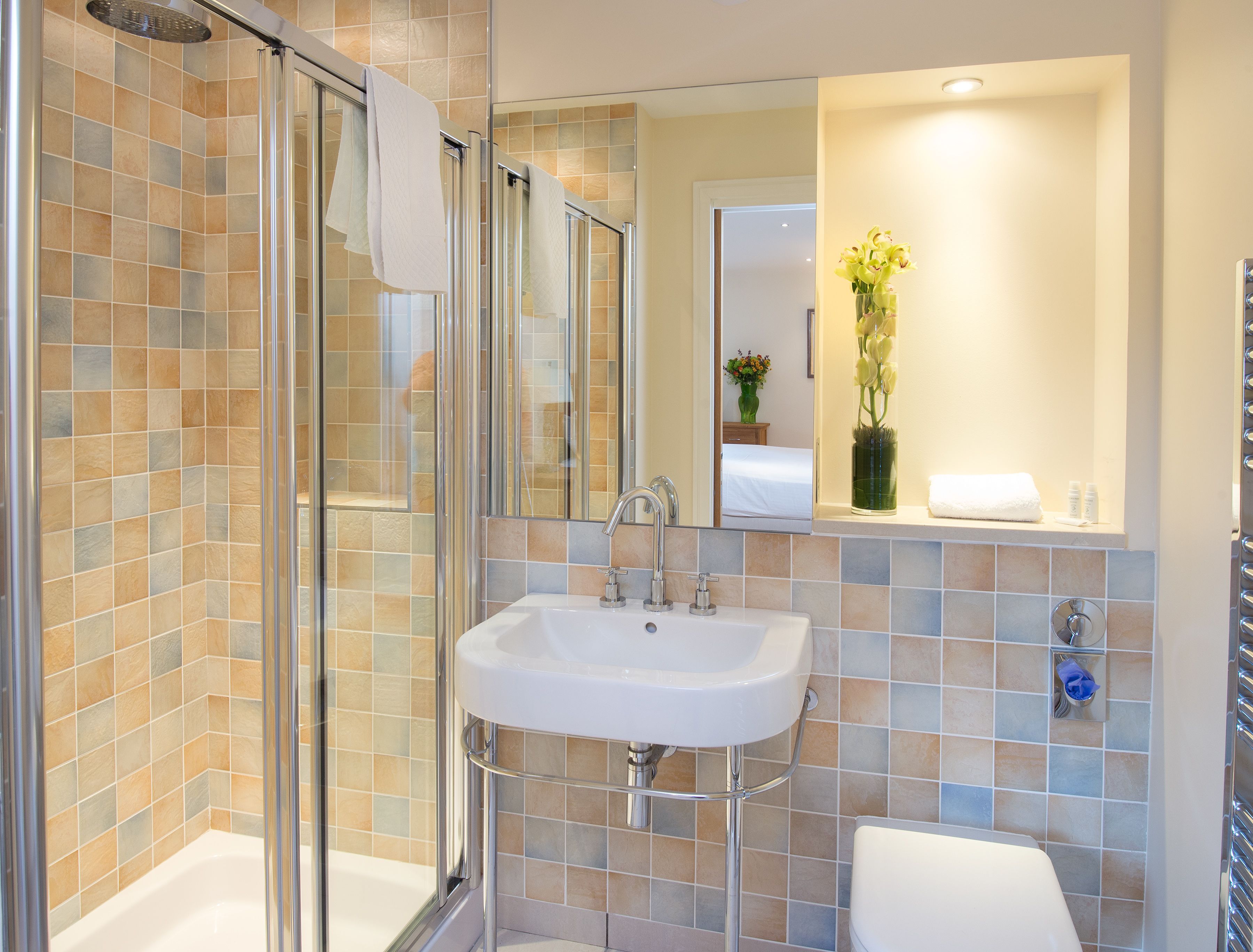 Un bagno con cabina doccia in vetro, un lavandino bianco e un water.