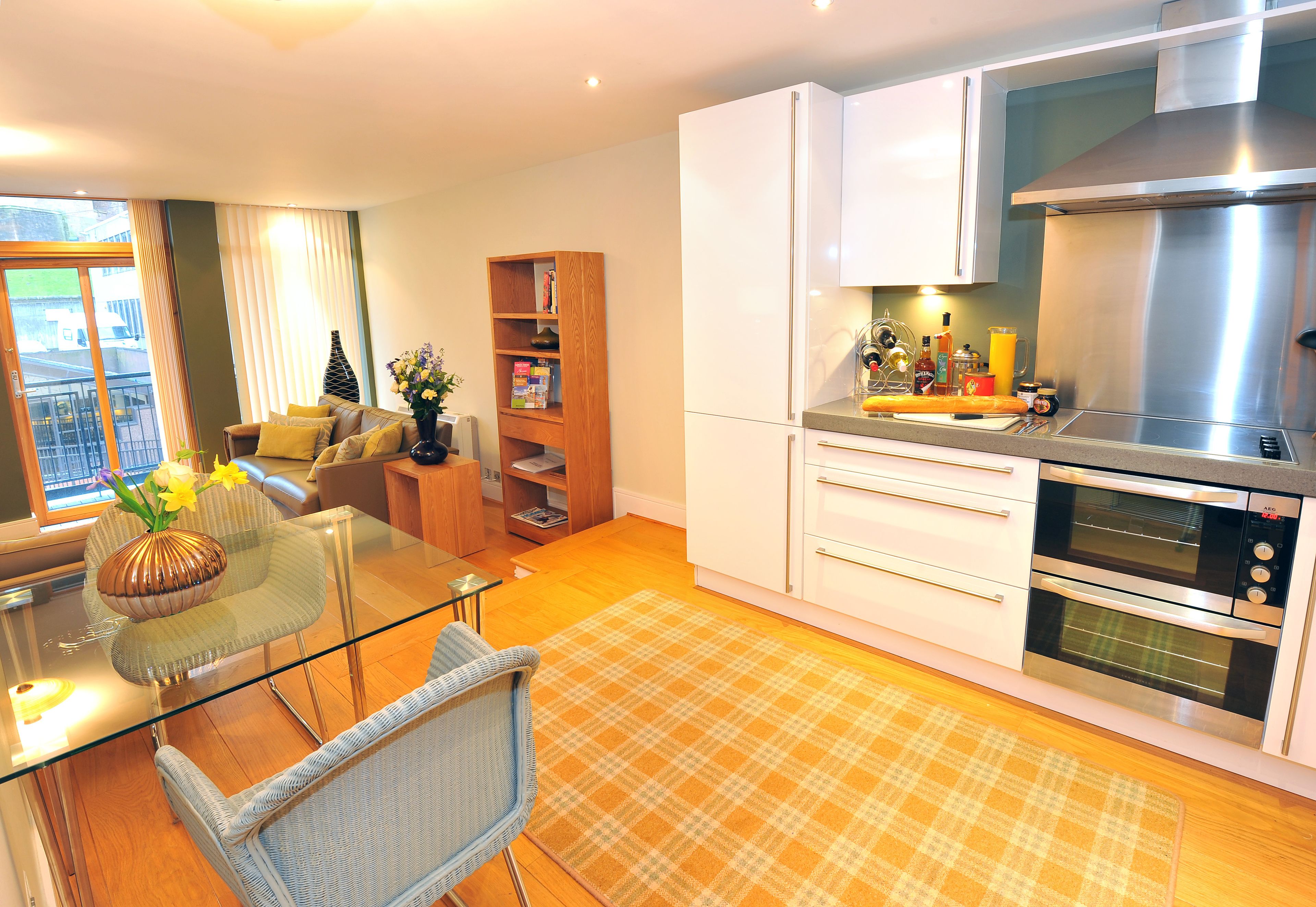 A modern kitchen with white cabinets, a stainless steel range hood, and a double oven.