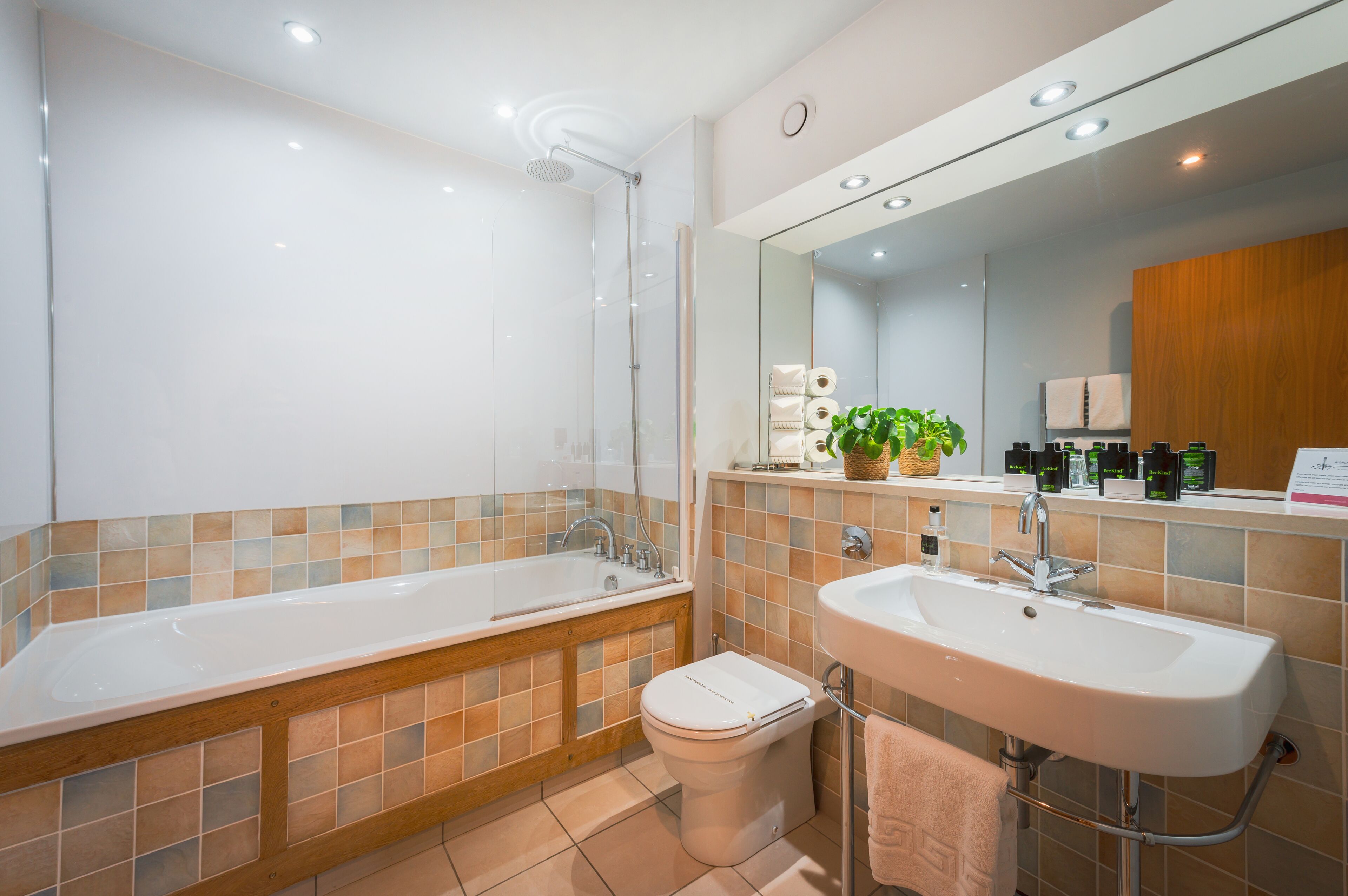 Une salle de bain moderne équipée d’une baignoire, de toilettes, d’un lavabo et d’un grand miroir.