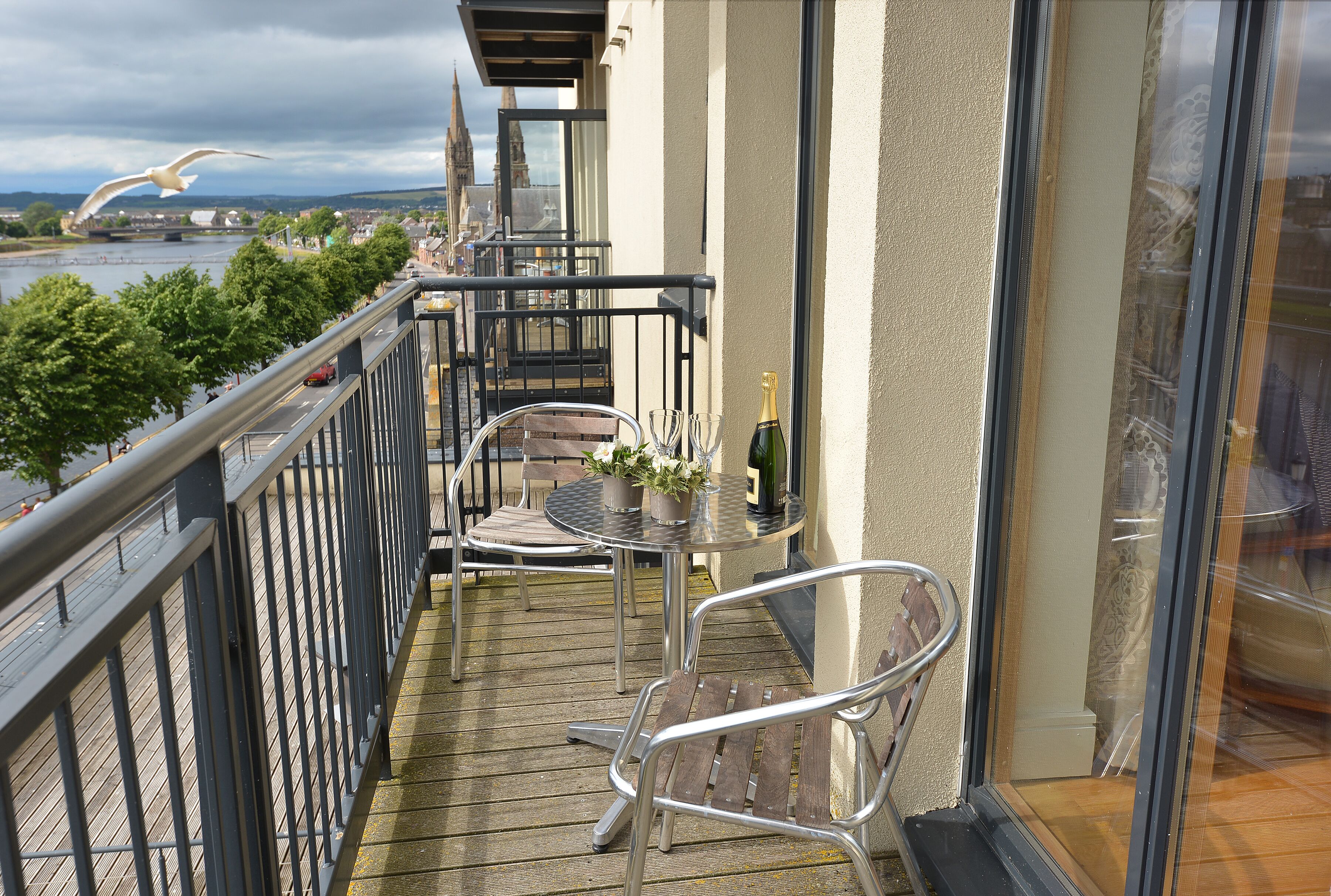 Un balcon avec une table, des chaises et une bouteille de champagne.