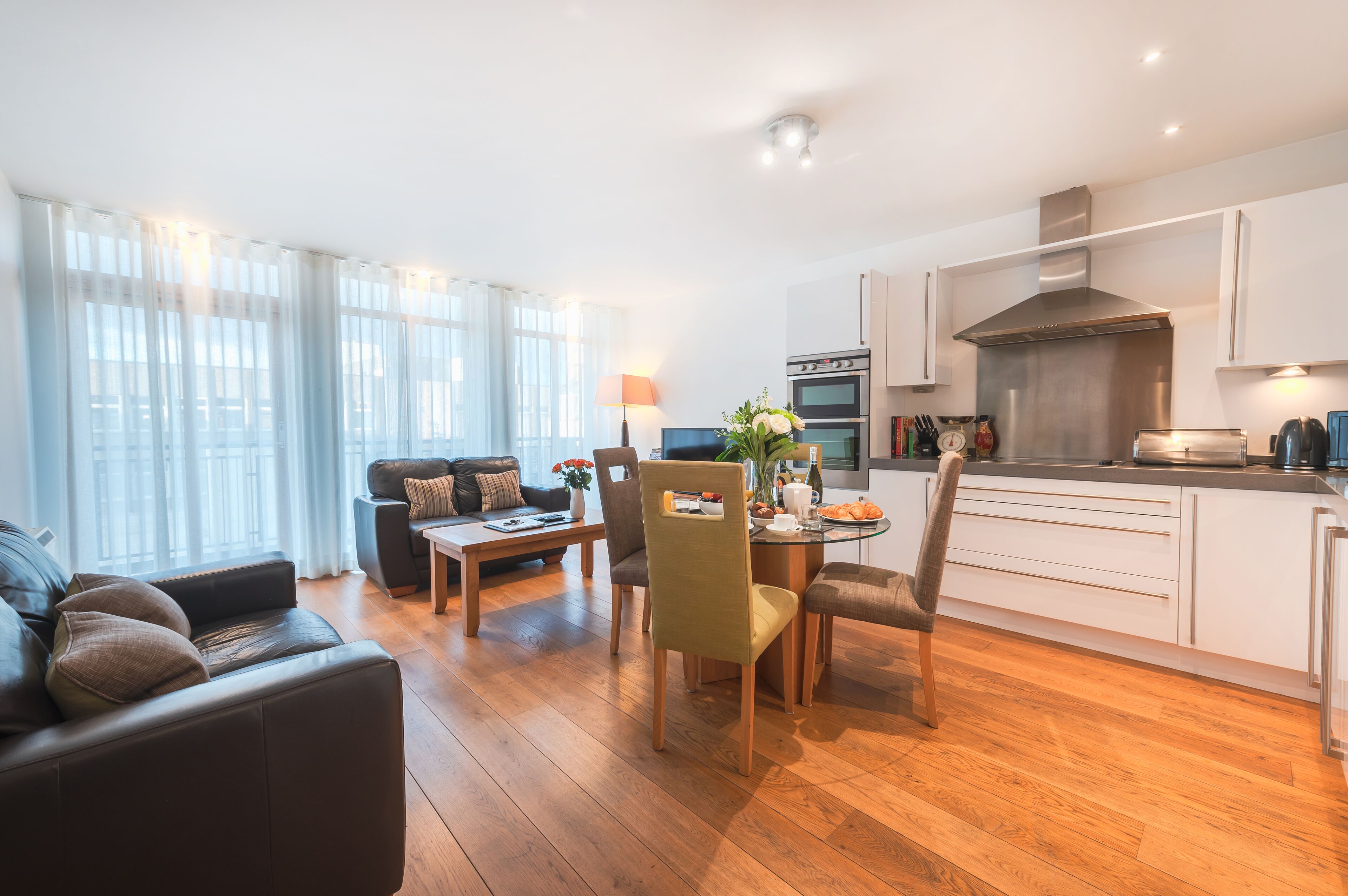A modern living room with a sofa, coffee table, and dining area.