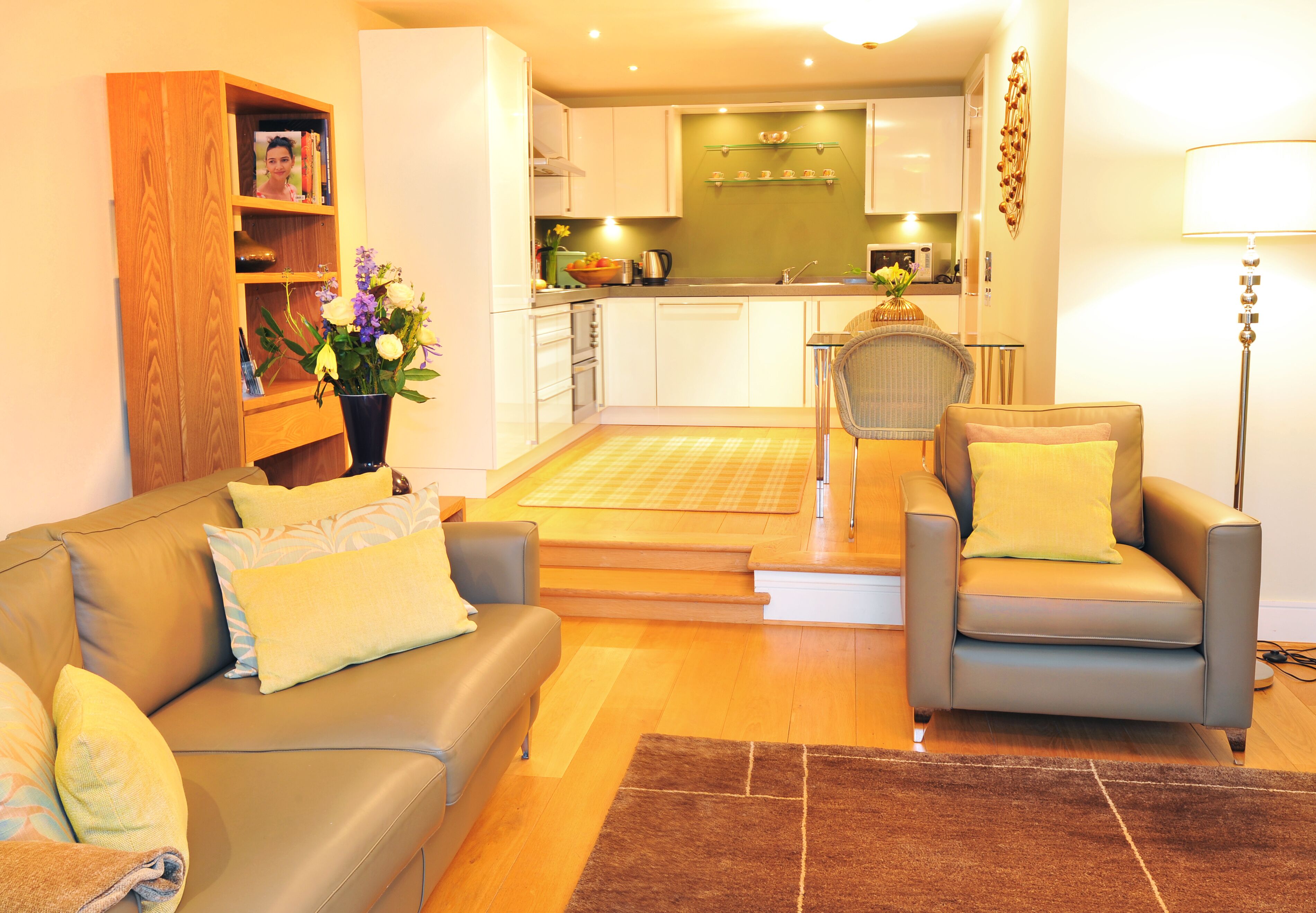 A modern living room with a sofa, armchairs, a coffee table, and a bookshelf.