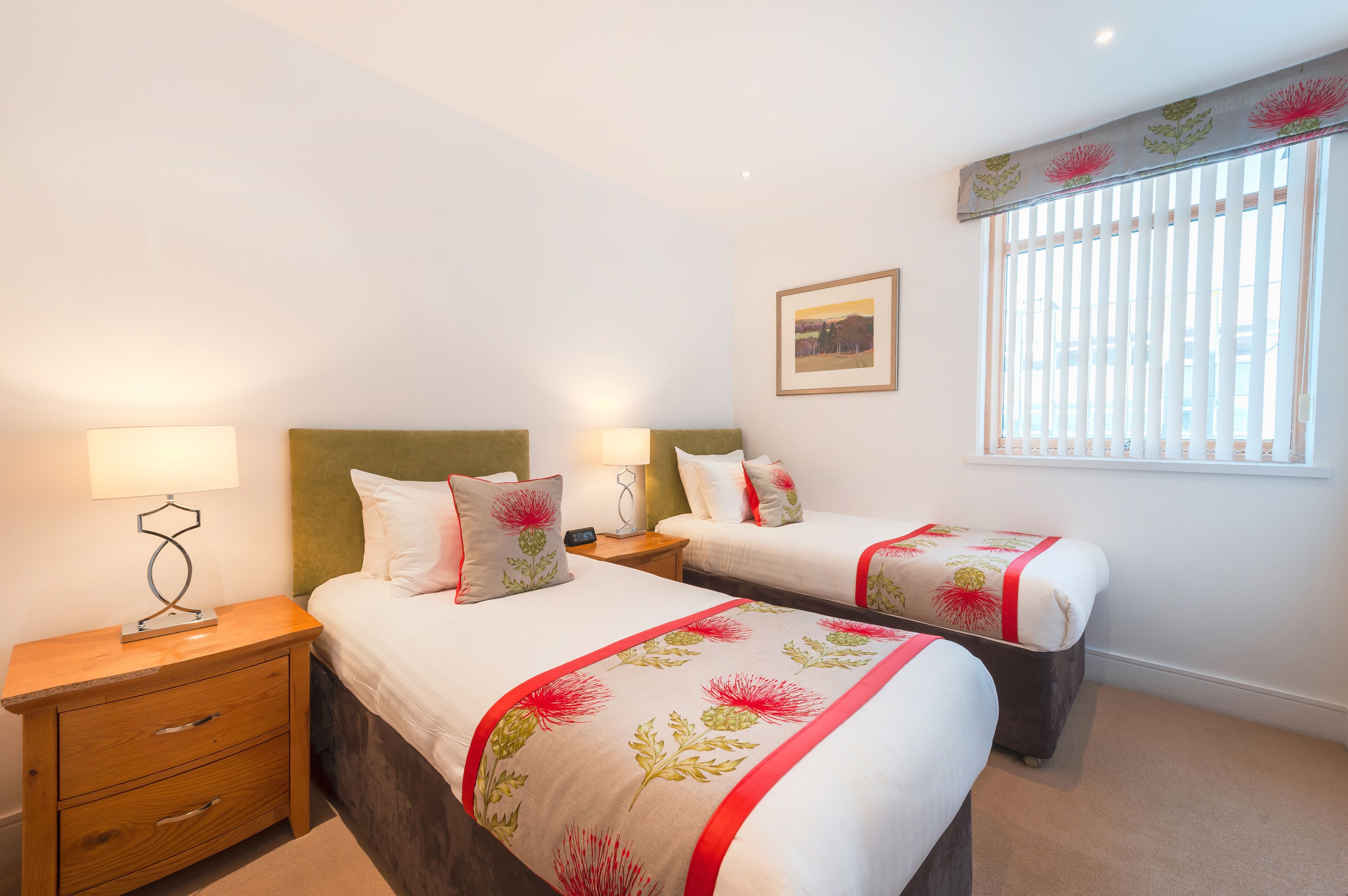 Una habitación de hotel con dos camas, una mesita de noche, una lámpara y una ventana con persianas.