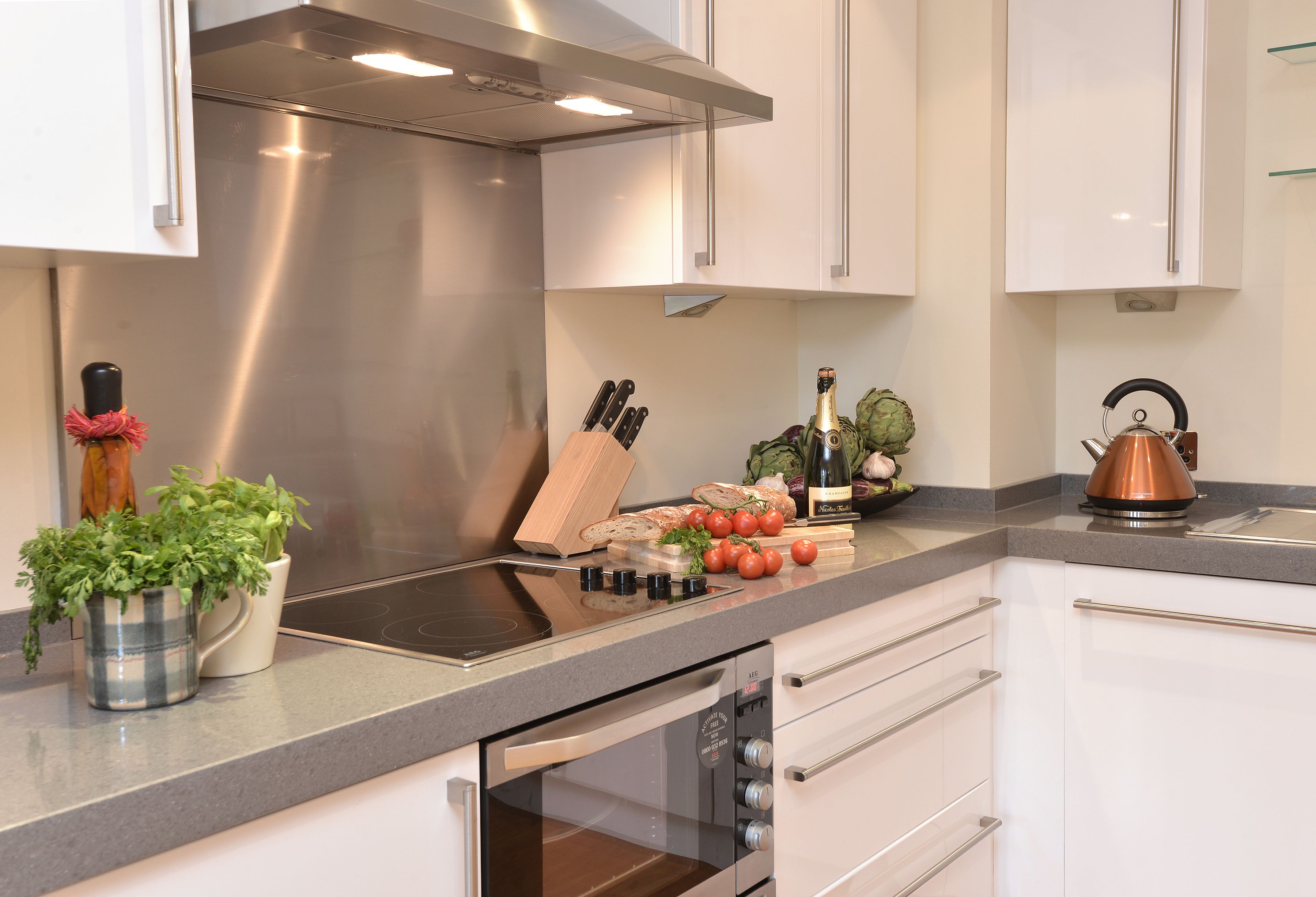 Una cucina moderna con elettrodomestici in acciaio inossidabile, forno integrato e una selezione di frutta e verdura fresca, oltre a utensili, sul piano di lavoro.
