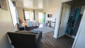 Une chambre d’hôtel moderne équipée d’un grand lit, d’un canapé, d’un bureau et d’un espace douche.