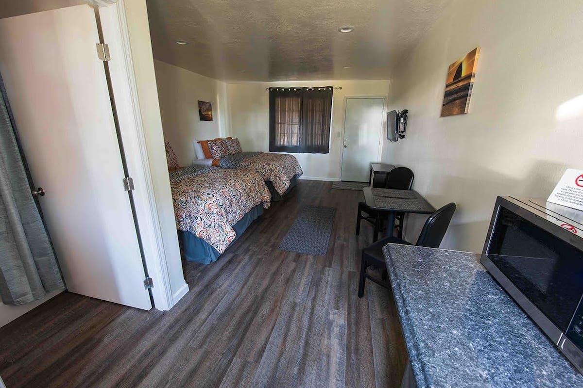 A compact hotel room with a bed, a desk, and a television.