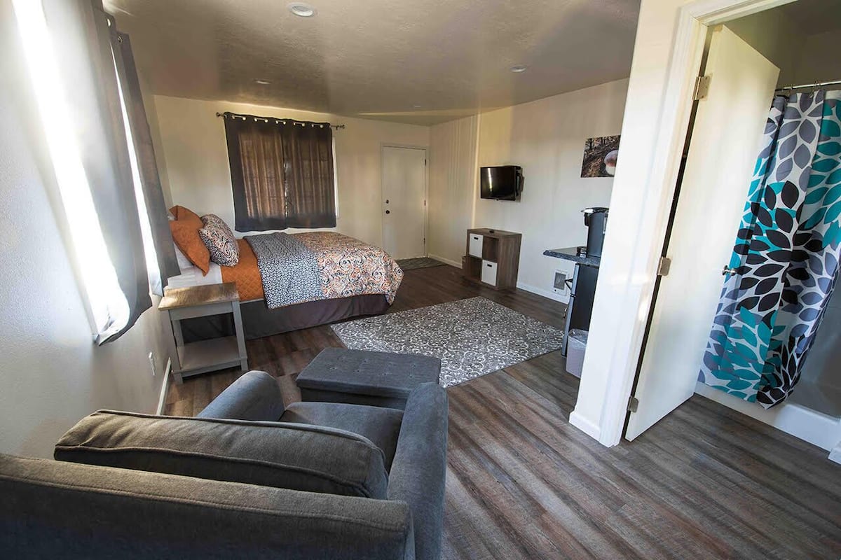 A compact room with a bed, a sofa, a small table, and a TV.