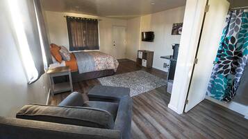 A compact room with a bed, a sofa, a small table, and a TV.