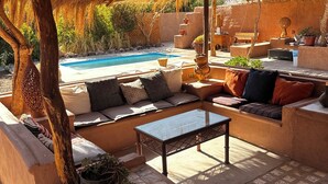 A covered outdoor seating area with a pool in the background. - Pat'ta Hoiri Hotel (San Pedro de Atacama)