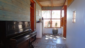 A wooden interior with a bench, a white refrigerator, and a large window. - Pat'ta Hoiri Hotel (San Pedro de Atacama)