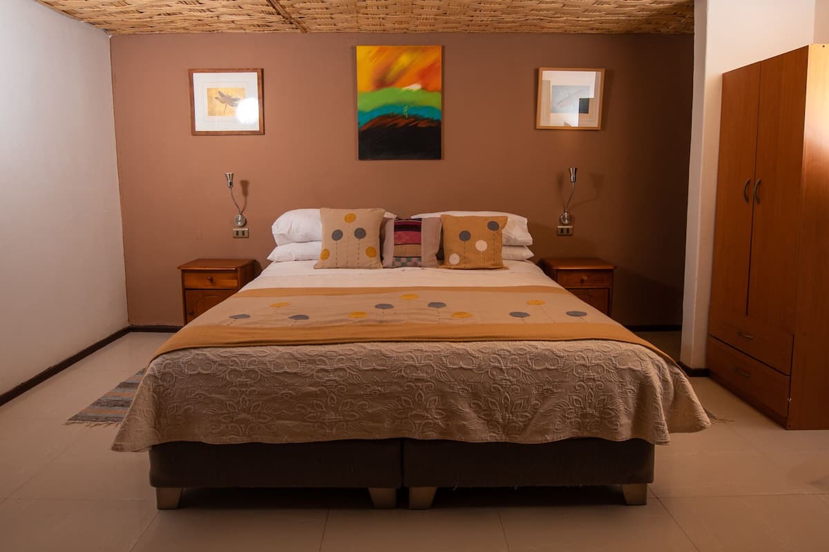 A double bed with a floral bedspread, two bedside tables, a nightstand, and a wardrobe.
