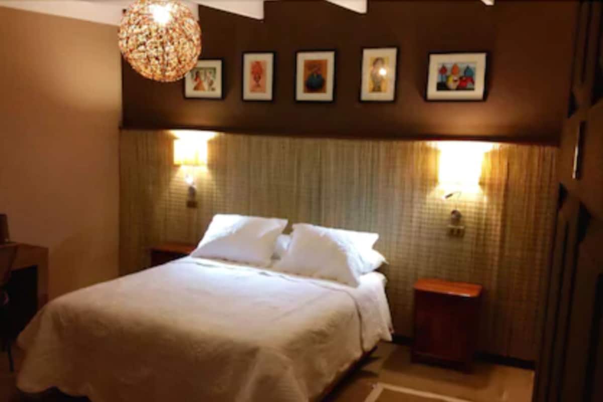 A hotel room with a large bed, two bedside tables, and a wall-mounted light fixture.