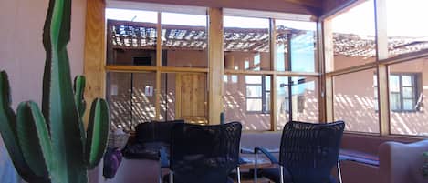 Una habitación con ventanas amplias, vigas de madera en el techo y una planta de cactus.