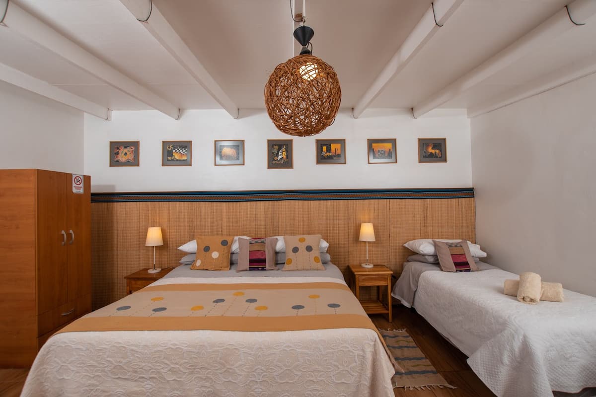 A hotel room with a large bed, two bedside tables, a wardrobe, and a hanging light fixture.