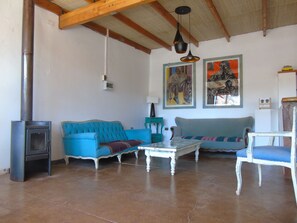 A living room with two sofas, a table, a chair, a fireplace, and artwork on the walls. - Pat'ta Hoiri Hotel (San Pedro de Atacama)