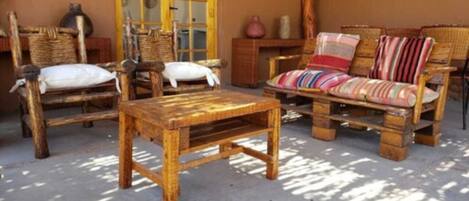A rustic room with wooden furniture including a sofa and chairs, a small wooden table, and a window with a view.
