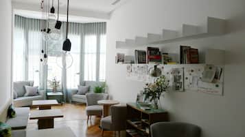 Een moderne woonkamer met een bank, stoelen, een salontafel en een boekenplank.