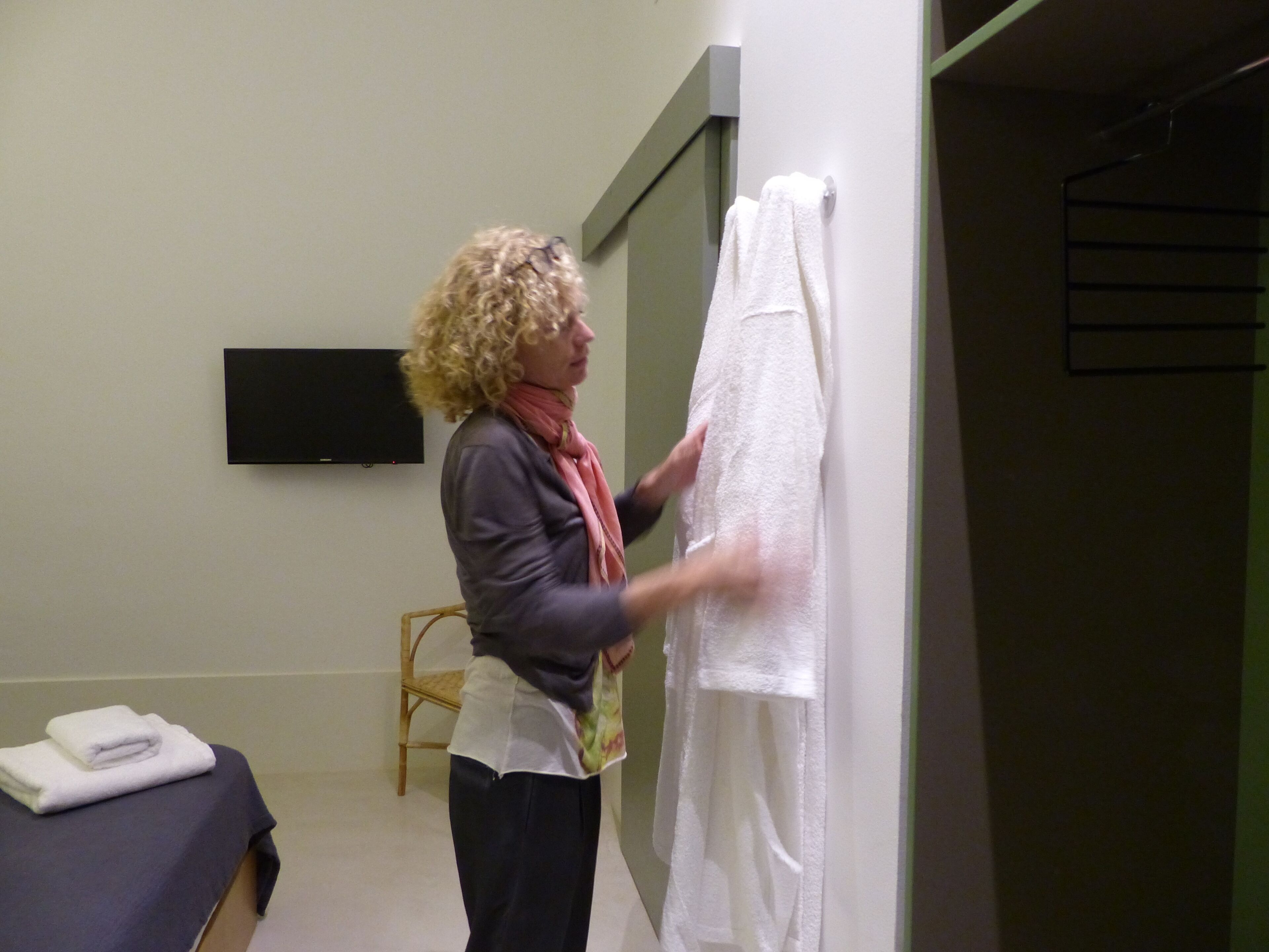 Una persona sosteniendo una toalla blanca en una habitación con una cama y una silla.