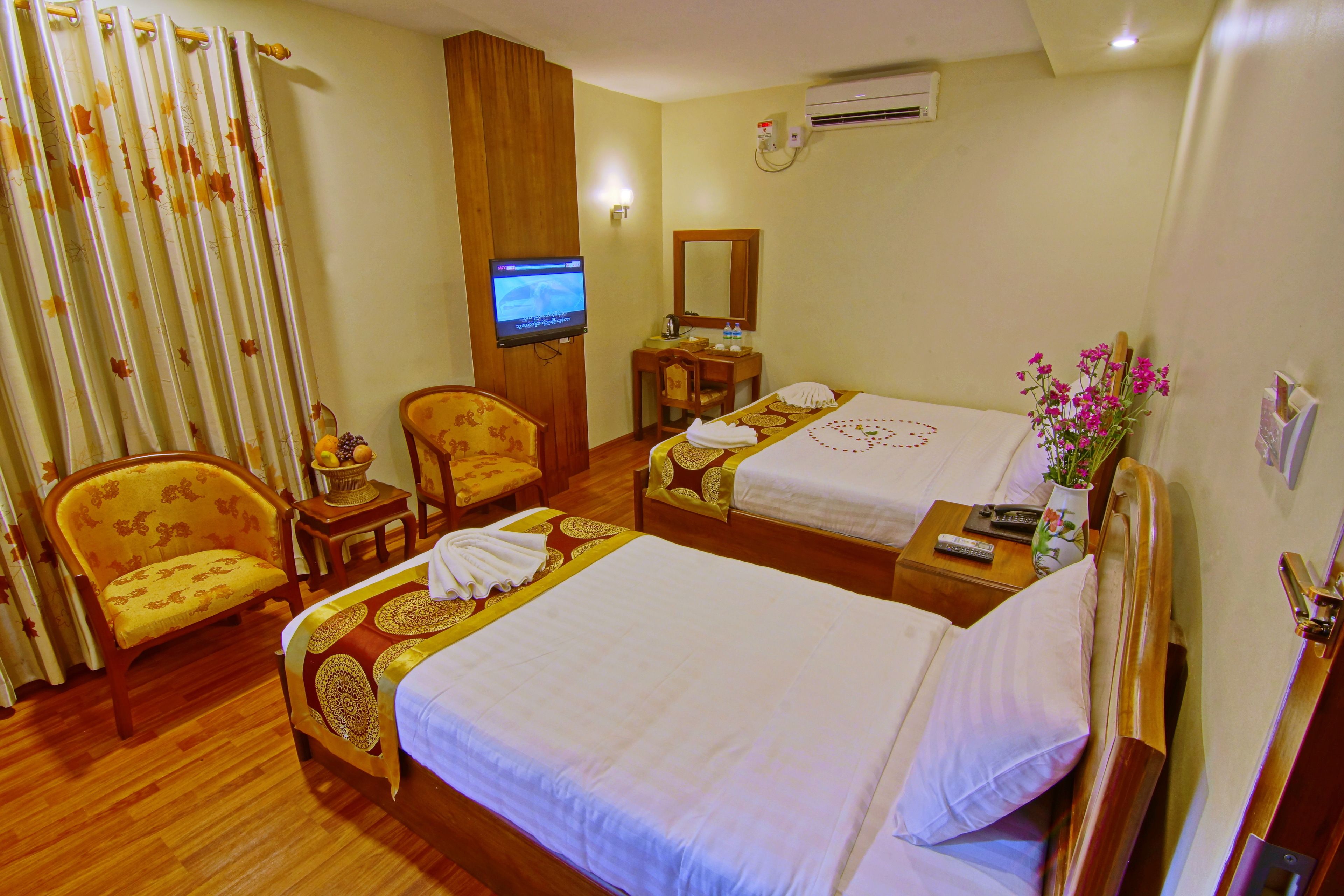 A hotel room with two beds, a television, a desk, and a chair.