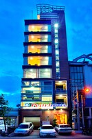 Un hotel de varios pisos con un letrero llamativo y un estacionamiento con automóviles.