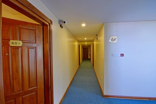 A hallway with a wooden door labeled '601', a security camera, and a sign '6F'.