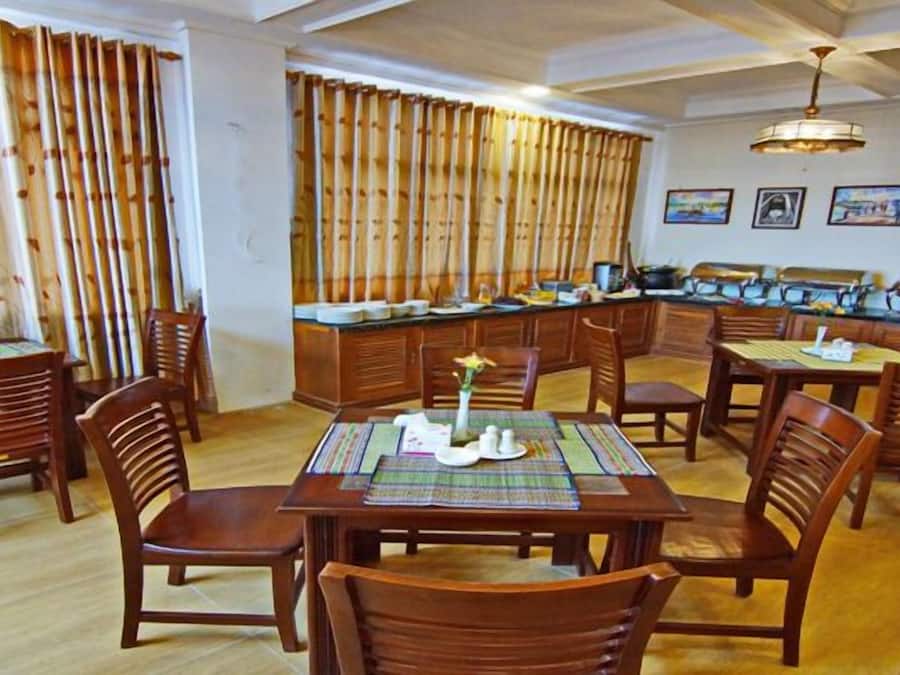 A dining area with wooden tables and chairs, bamboo curtains, and a ceiling fan.